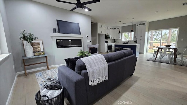 living area featuring a ceiling fan, visible vents, light wood-style flooring, and baseboards