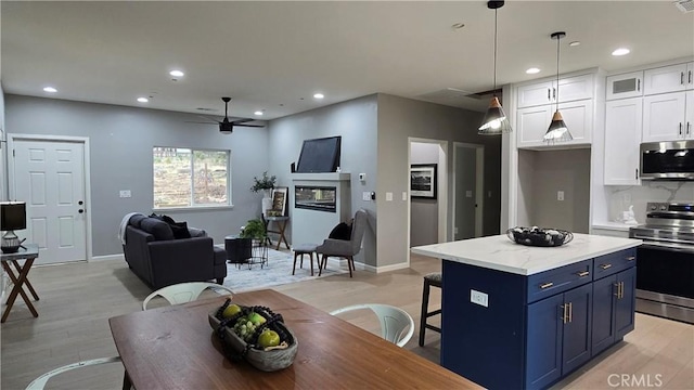 kitchen featuring a center island, pendant lighting, stainless steel appliances, white cabinets, and blue cabinets