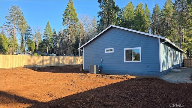 view of side of property with a fenced backyard and central air condition unit