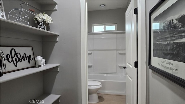 bathroom featuring washtub / shower combination, toilet, and wood finished floors