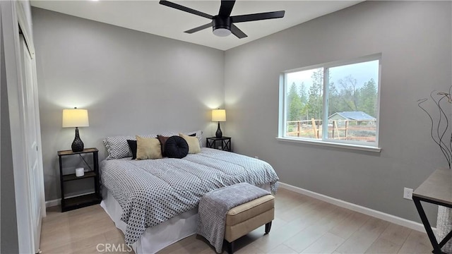 bedroom with a ceiling fan, light wood finished floors, and baseboards