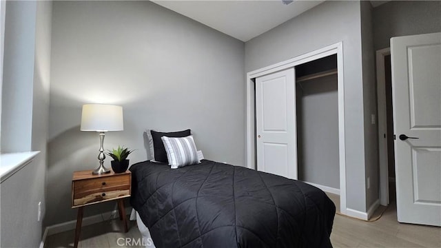 bedroom with baseboards, a closet, and light wood-style floors