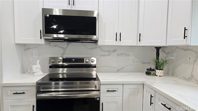 kitchen featuring light stone counters, appliances with stainless steel finishes, white cabinetry, and tasteful backsplash