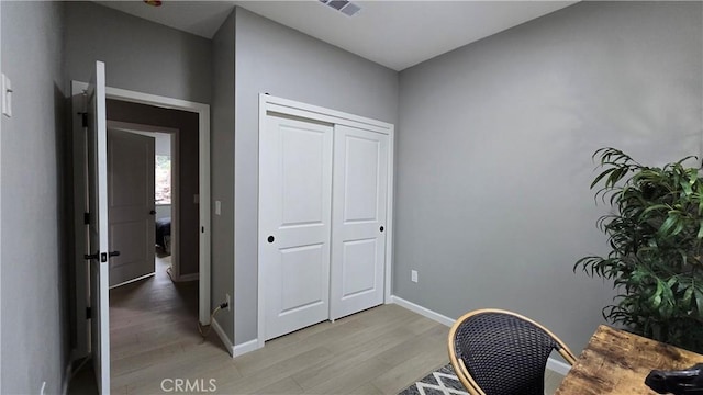 office featuring light wood finished floors, visible vents, and baseboards