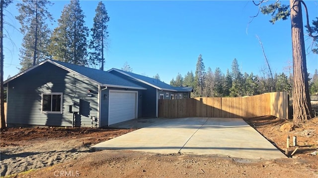 view of side of home featuring a garage, fence, and concrete driveway