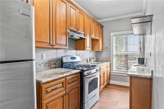 kitchen with light stone countertops, under cabinet range hood, stainless steel appliances, and crown molding