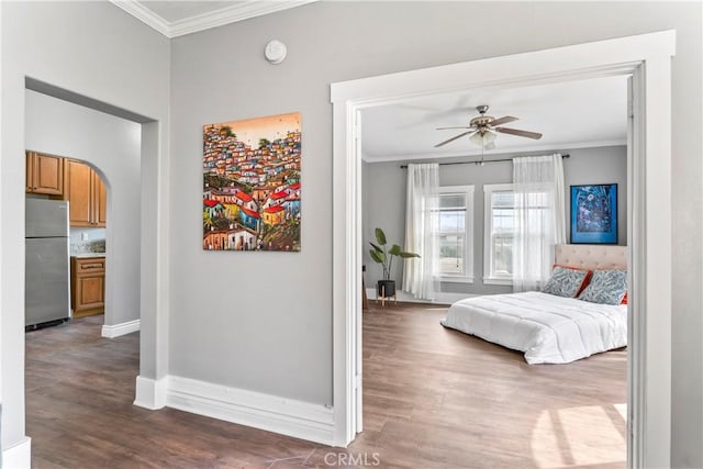 bedroom featuring ornamental molding, arched walkways, dark wood finished floors, and freestanding refrigerator