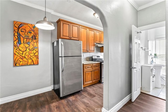 kitchen with brown cabinets, appliances with stainless steel finishes, arched walkways, and ornamental molding