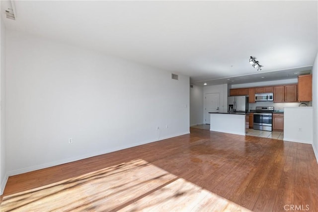 unfurnished living room featuring light wood-type flooring, visible vents, and baseboards