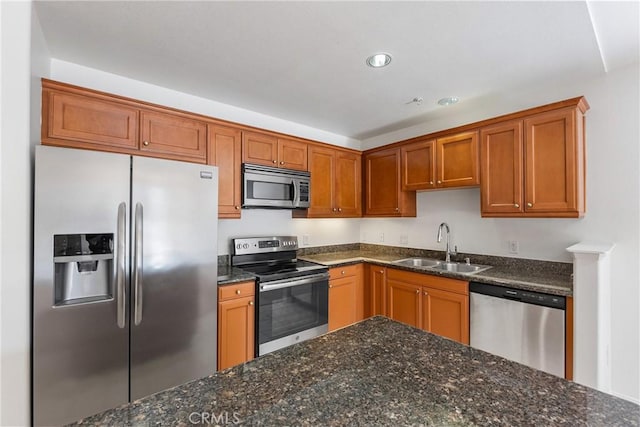 kitchen featuring dark stone counters, stainless steel appliances, and a sink