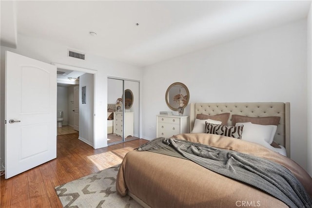 bedroom featuring a closet, wood finished floors, and visible vents