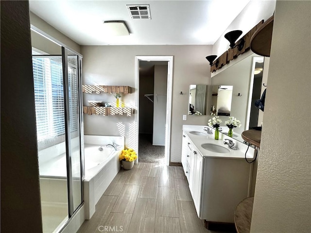 full bath featuring a bath, double vanity, visible vents, and a sink