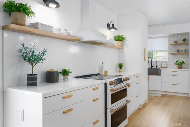 kitchen featuring open shelves, a sink, double oven range, tasteful backsplash, and white cabinetry