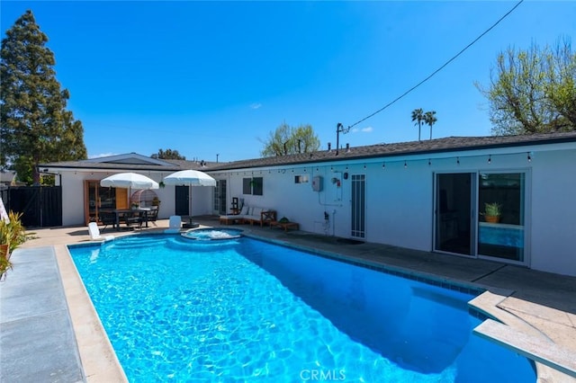 view of swimming pool featuring fence, a pool with connected hot tub, and a patio area
