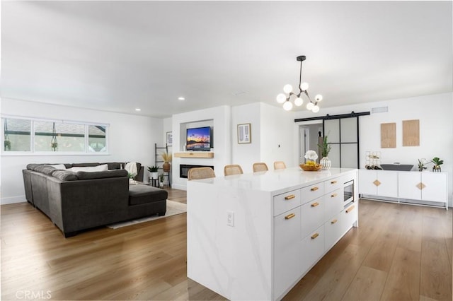 kitchen featuring built in microwave, wood finished floors, a barn door, and white cabinetry