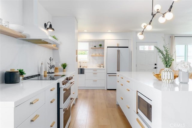 kitchen featuring under cabinet range hood, open shelves, high quality appliances, light countertops, and white cabinets