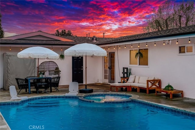 rear view of house with french doors, stucco siding, a pool with connected hot tub, and a patio area