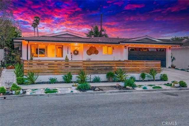view of front of house with stucco siding, a garage, concrete driveway, and a fenced front yard