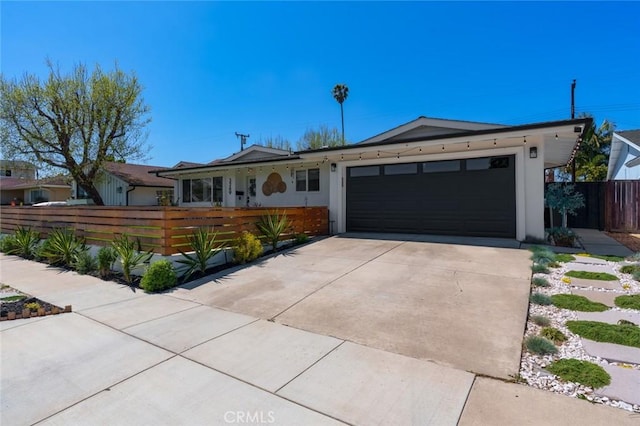 ranch-style home featuring a garage, fence private yard, and concrete driveway