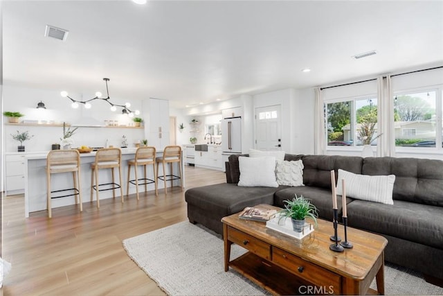 living room with visible vents, recessed lighting, and light wood-style flooring