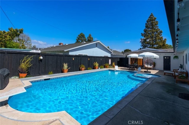 view of swimming pool featuring a pool with connected hot tub, a diving board, a fenced backyard, and a patio area