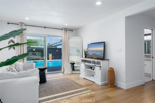 living area featuring baseboards, recessed lighting, and light wood finished floors