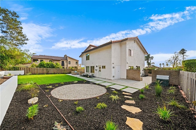 rear view of property featuring a fenced backyard, a tile roof, a yard, stucco siding, and a patio area