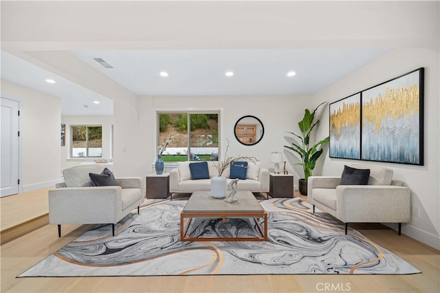 living room with recessed lighting, visible vents, baseboards, and wood finished floors