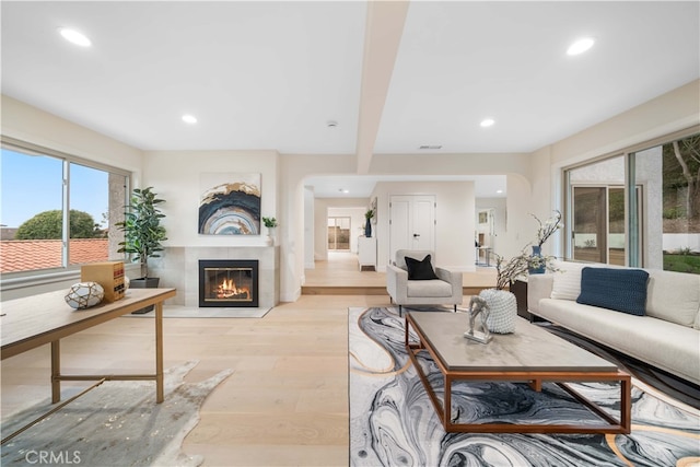 living area featuring light wood-type flooring, recessed lighting, visible vents, and a glass covered fireplace