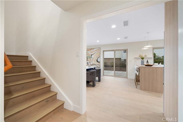 staircase with baseboards, wood finished floors, visible vents, and recessed lighting