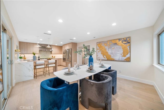 dining room with light wood finished floors, baseboards, and recessed lighting