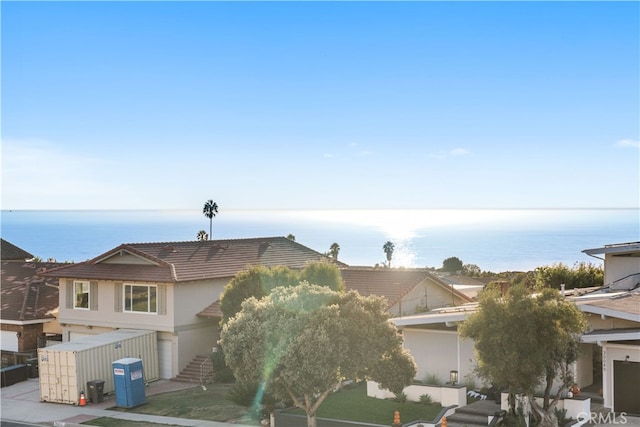 view of front of property featuring a water view, a tiled roof, stairway, and stucco siding