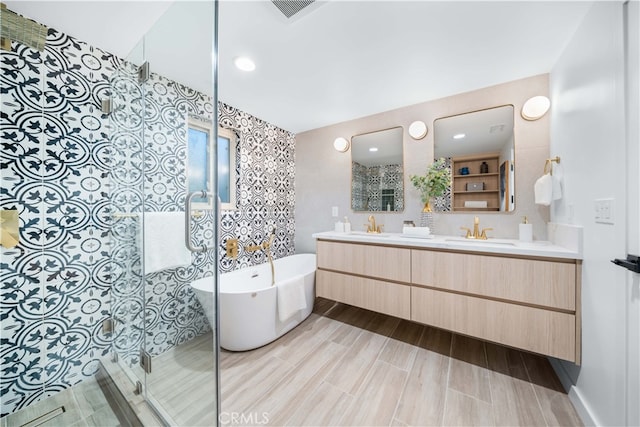 bathroom featuring double vanity, a stall shower, visible vents, a freestanding tub, and a sink