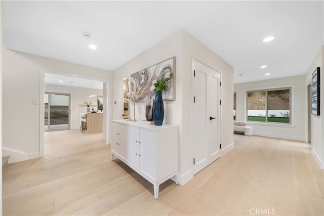 corridor featuring light wood-type flooring, baseboards, and recessed lighting