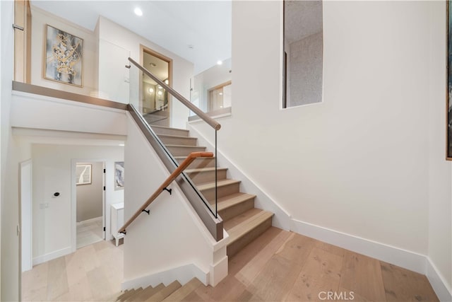 stairway featuring a high ceiling, wood finished floors, and baseboards