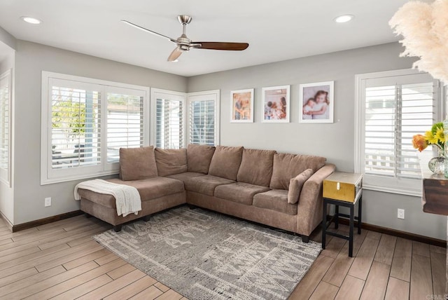 living area featuring baseboards, light wood-type flooring, and a healthy amount of sunlight