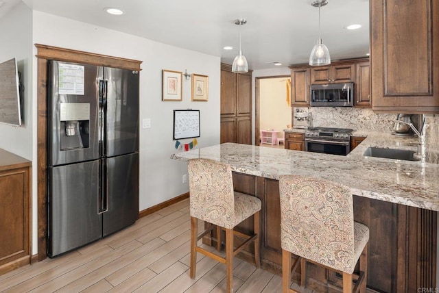 kitchen featuring stainless steel appliances, a breakfast bar, a sink, and light stone counters