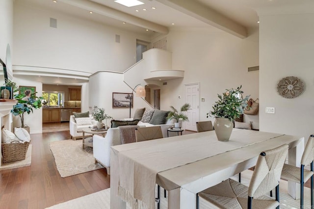 dining area with arched walkways, beam ceiling, visible vents, wood finished floors, and high vaulted ceiling