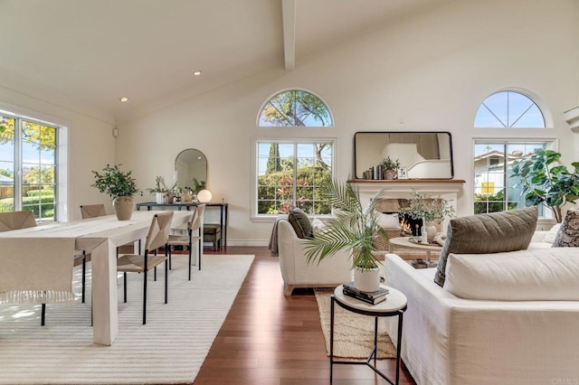 living area with high vaulted ceiling, a warm lit fireplace, dark wood finished floors, and beamed ceiling