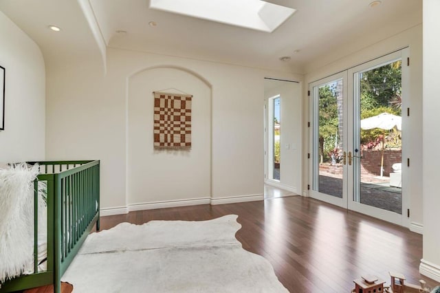 interior space featuring recessed lighting, dark wood-type flooring, a skylight, baseboards, and french doors