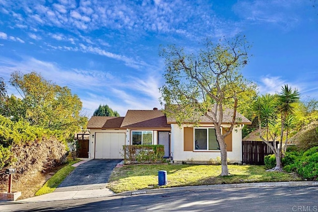 view of front of house with aphalt driveway, stucco siding, a front yard, fence, and a garage