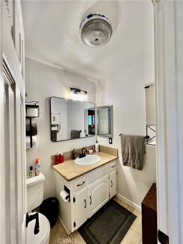 bathroom featuring toilet, tile patterned floors, baseboards, and vanity