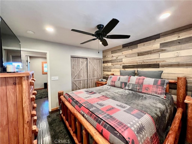 bedroom with recessed lighting, dark wood-type flooring, a ceiling fan, wood walls, and baseboards