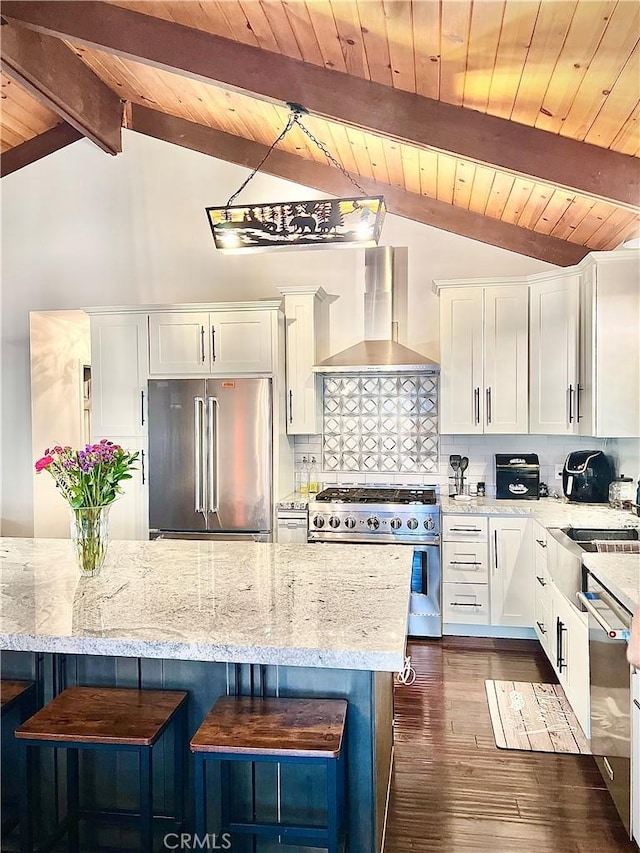 kitchen with premium appliances, wall chimney range hood, and white cabinets