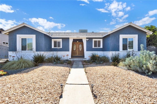 ranch-style house featuring fence and stucco siding