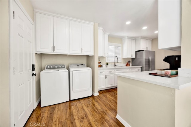 laundry area featuring laundry area, wood finished floors, independent washer and dryer, a sink, and recessed lighting