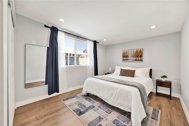 bedroom with baseboards, wood finished floors, and recessed lighting