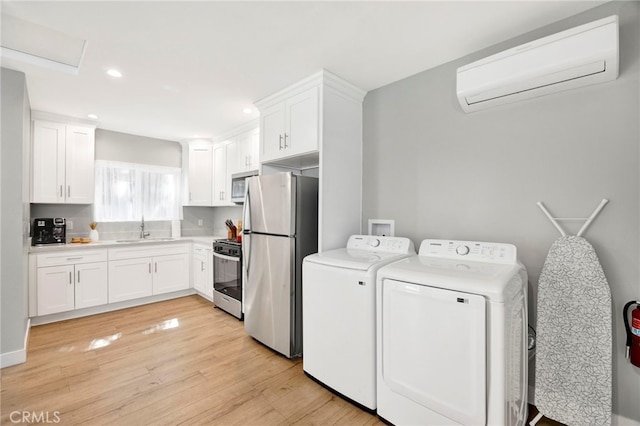 laundry area with laundry area, light wood-style flooring, separate washer and dryer, a sink, and a wall mounted AC