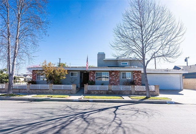 view of front of home featuring a garage, driveway, brick siding, and a fenced front yard