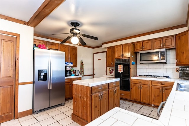 kitchen featuring a center island, tile countertops, stainless steel appliances, decorative backsplash, and brown cabinetry